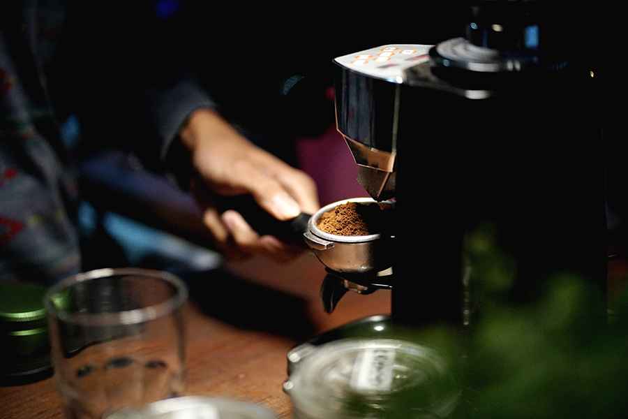 a barista places freshly ground coffee into the espresso machine