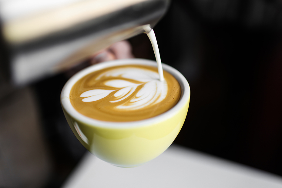 a barista pours milk into coffee to create latte art.